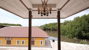Un espacio al aire libre cubierto con un edificio amarillo, un río y un área boscosa al fondo.