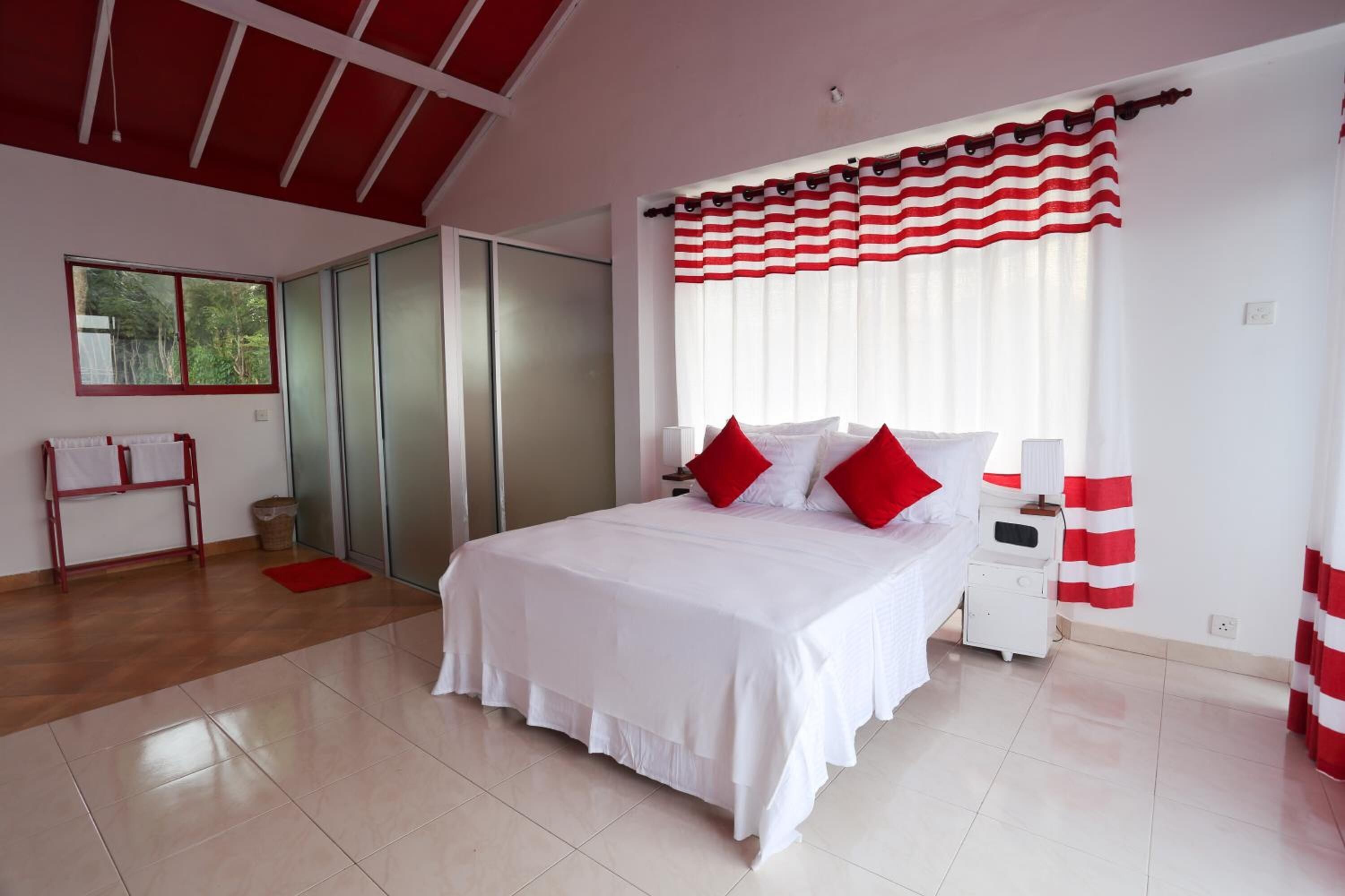 A bedroom with a bed, a nightstand, a wardrobe, and a window with curtains.