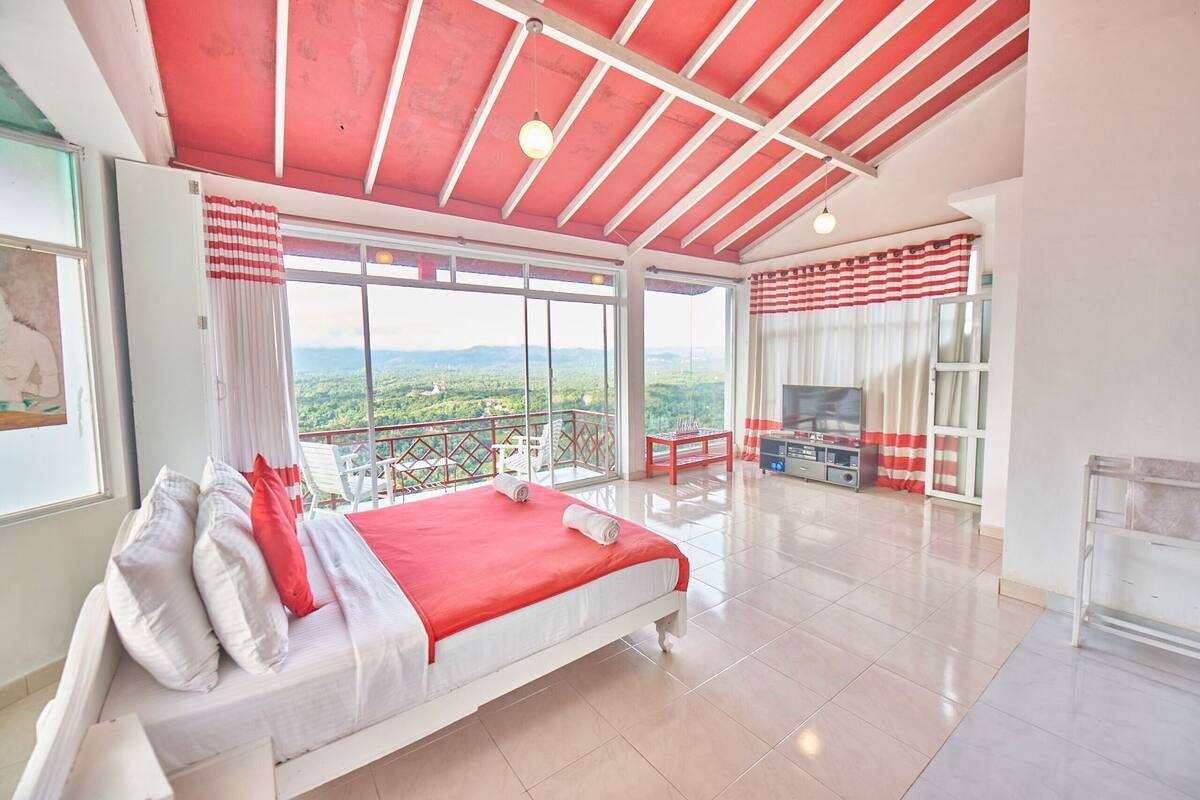 Un dormitorio con cama, televisión y balcón con vistas.