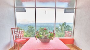 A room with a red table, a chair, and a view of mountains through large windows. - Redhill Kandy (Kandy)
