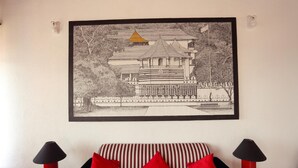 A framed black and white architectural drawing on a wall above a striped sofa with red cushions. - Redhill Kandy (Kandy)