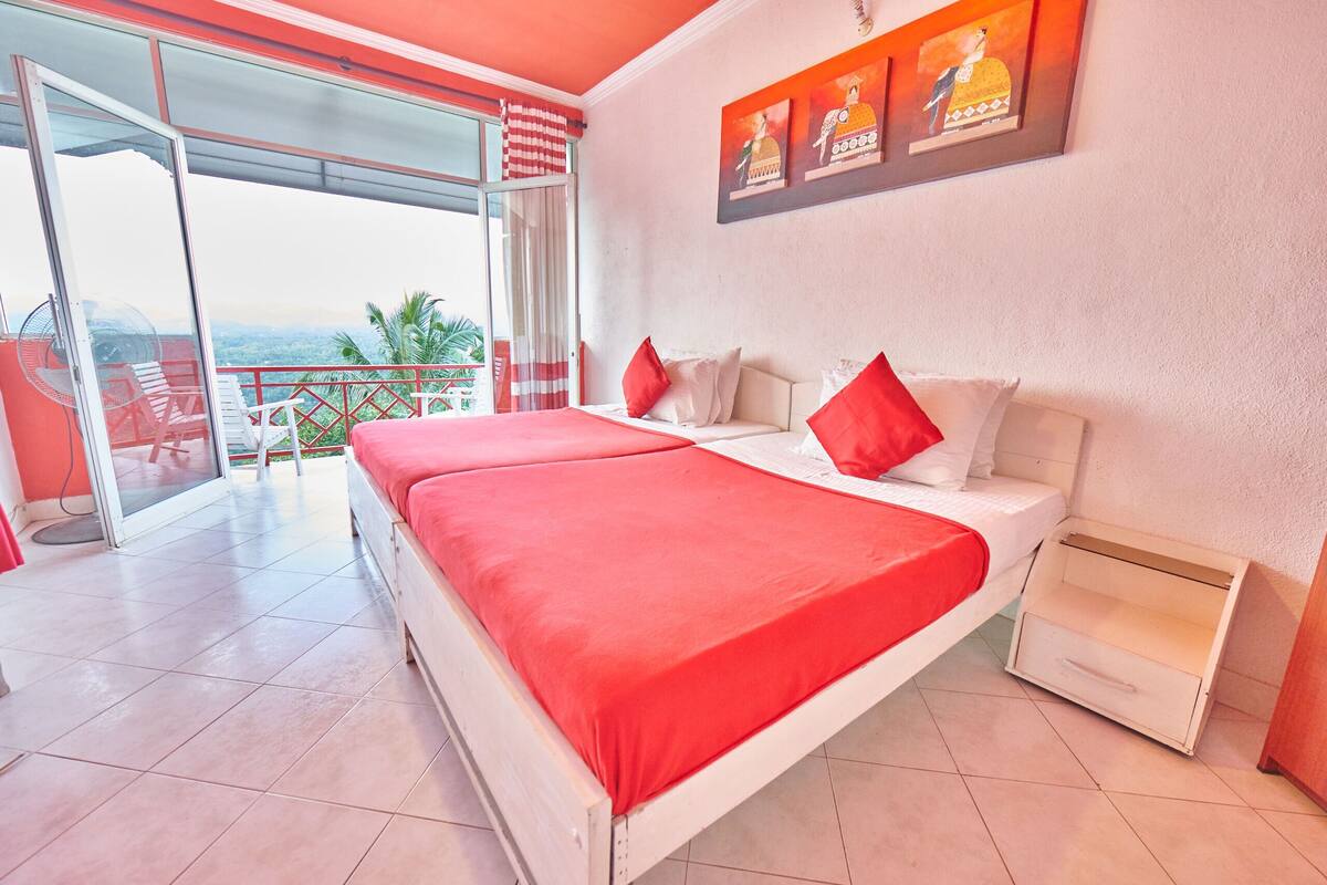 Habitación de hotel con una cama grande, puerta corredera de vidrio a un balcón y vista al paisaje.