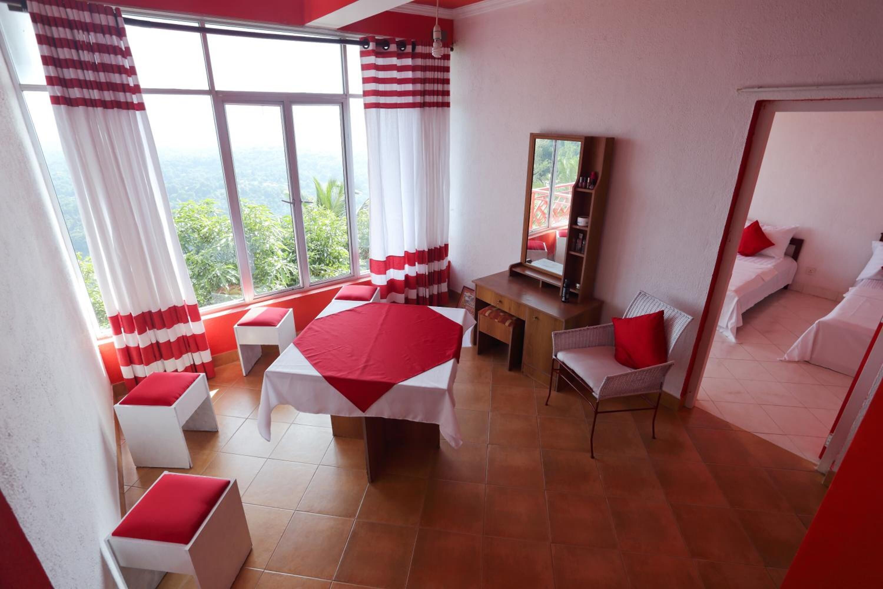A hotel room with a large bed, a desk, a chair, and a view of the outdoors.