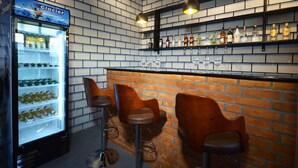 A bar area with a brick wall, a Glacier branded refrigerator, and bar stools.