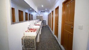A hotel corridor with a row of bathrooms, each with a mirror, sink, and towel rack.