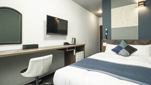 A modern hotel room with a bed, a desk, a chair, a television, and a mirror. - Hotel AreaOne Tokai (Tokai-mura)