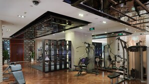 A modern gym with exercise equipment, a wooden floor, and a glass partition wall. - Beijing Baifuyi Apartment Dongzhimen (Beijing)