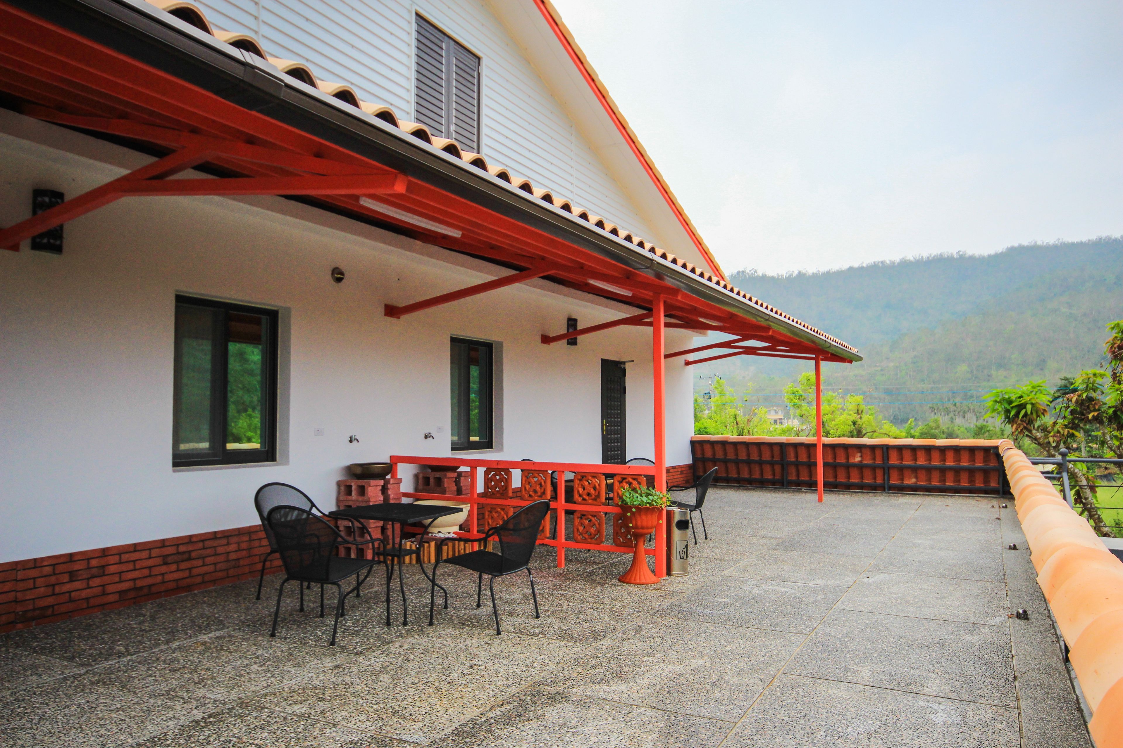 A covered patio with outdoor seating, a brick wall, and a view of a hilly landscape.
