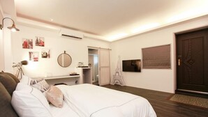 Een slaapkamer met een bed, een bureau, een stoel, een spiegel en een deur.