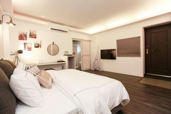 Un dormitorio con cama, escritorio, silla, espejo y puerta.