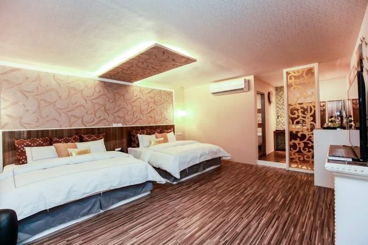 Una habitación de hotel con dos camas, piso de madera, papel tapiz estampado y un separador decorativo.