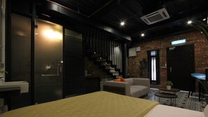 A modern hotel room with a bed, a sofa, a small table, and a staircase leading to an upper level. - Lorong Jambatan Melaka (Malacca City)