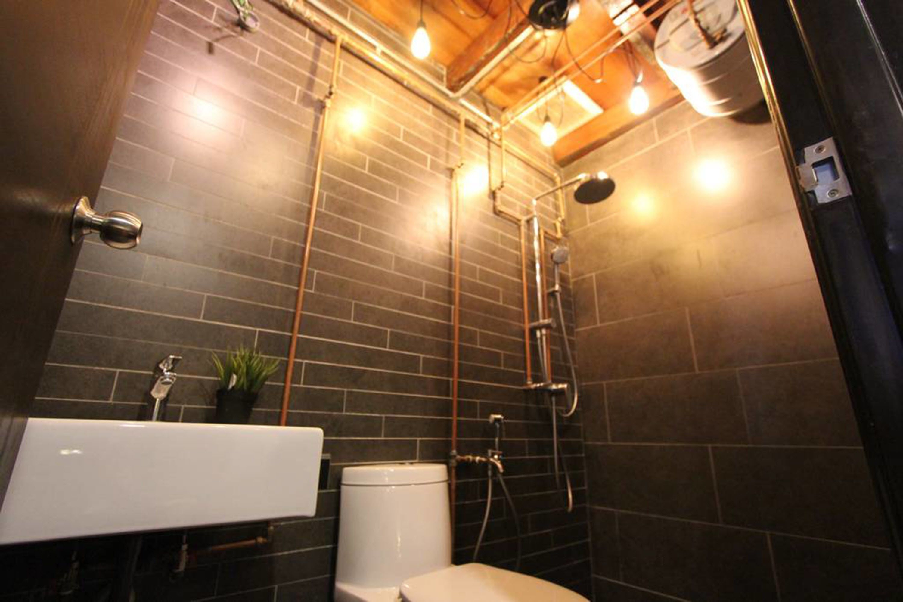 A modern bathroom with a black tiled wall, a white sink, and a toilet.
