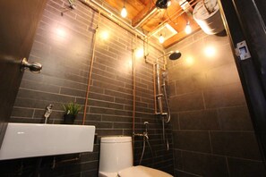 A modern bathroom with a black tiled wall, a white sink, and a toilet.