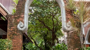 A traditional archway leading to a staircase surrounded by potted plants and a lush green backdrop. - New Patong Premier Resort (Patong)