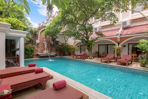 A pool area with lounge chairs and a small waterfall feature. - New Patong Premier Resort (Patong)