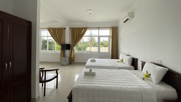 Een hotelkamer met twee bedden, een televisie, een bureau en een stoel.