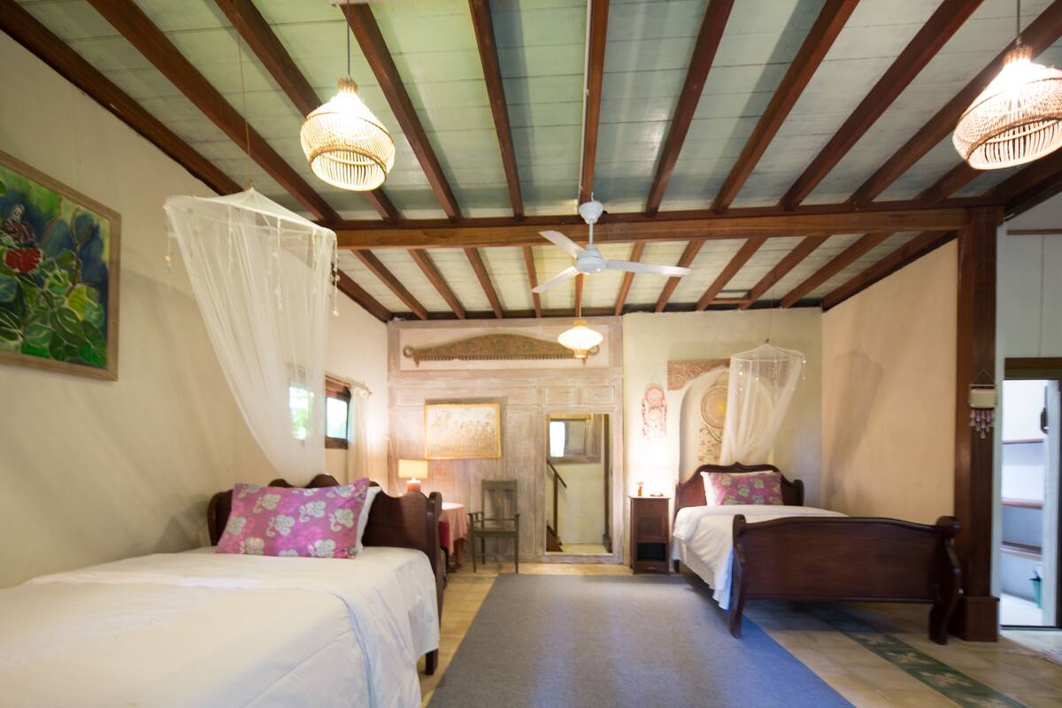 A bedroom with two beds, a ceiling fan, and a staircase leading to an upper level.