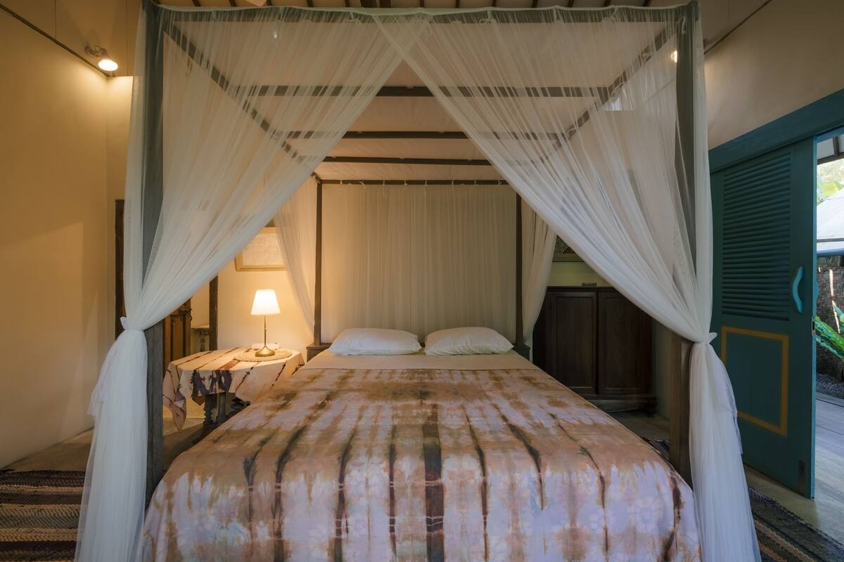 A bed with a canopy, a bedside lamp, and a nightstand.