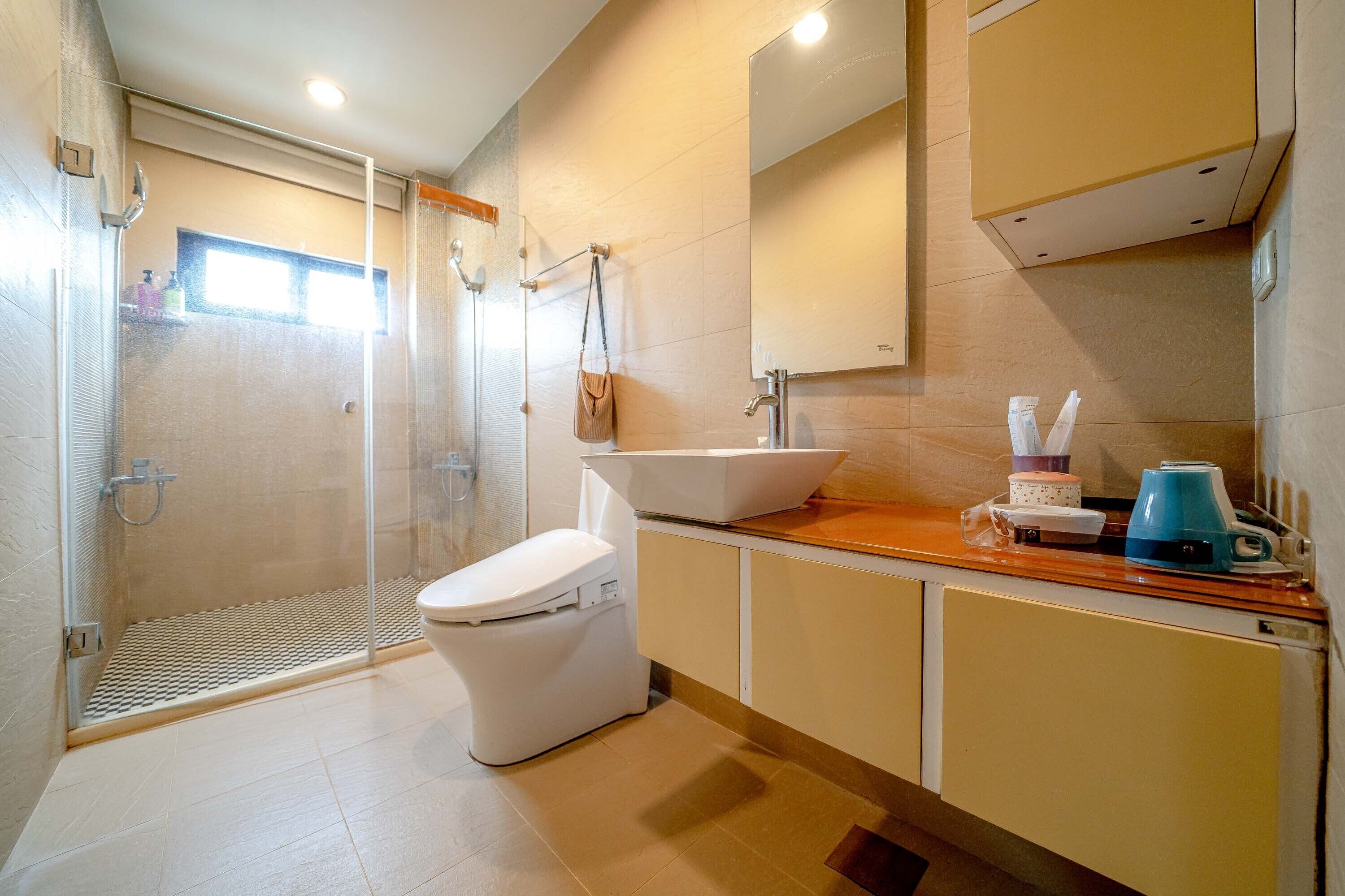 Een moderne badkamer met een douche, toilet, wastafel en spiegel.