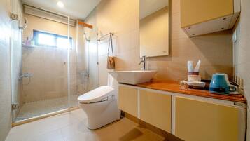 A modern bathroom with a shower, toilet, sink, and a mirror.