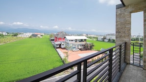 A balcony with a view of a green field and houses in the distance. - My Sweetie B&B (Dongshan)
