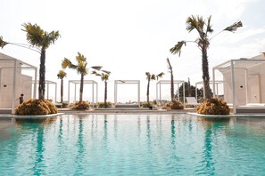 Une piscine bordée de palmiers et entourée de constructions blanches.