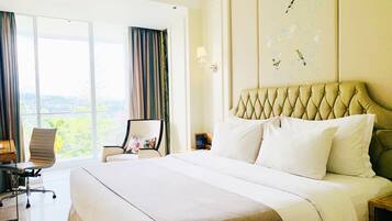 A hotel room with a large bed, a chair, a desk, and a view of the outdoors.