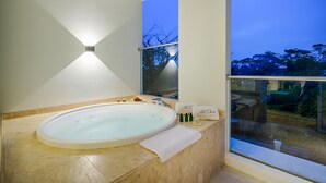 Une salle de bain moderne avec une grande baignoire ovale, une douche en verre et une vue sur les arbres par une grande fenêtre.
