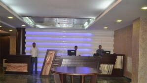 A reception area with a modern design, featuring a reception desk, a round table, and a staircase. - Hotel Patliputra Nirvanaa (Patna)