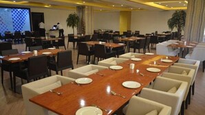 A conference room with multiple tables and chairs, equipped with laptops and a presentation screen. - Hotel Patliputra Nirvanaa (Patna)