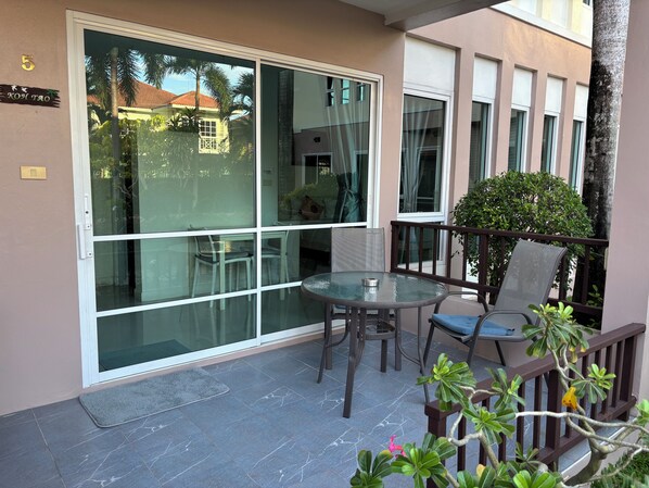 A balcony with a glass door, a round table, and two chairs.