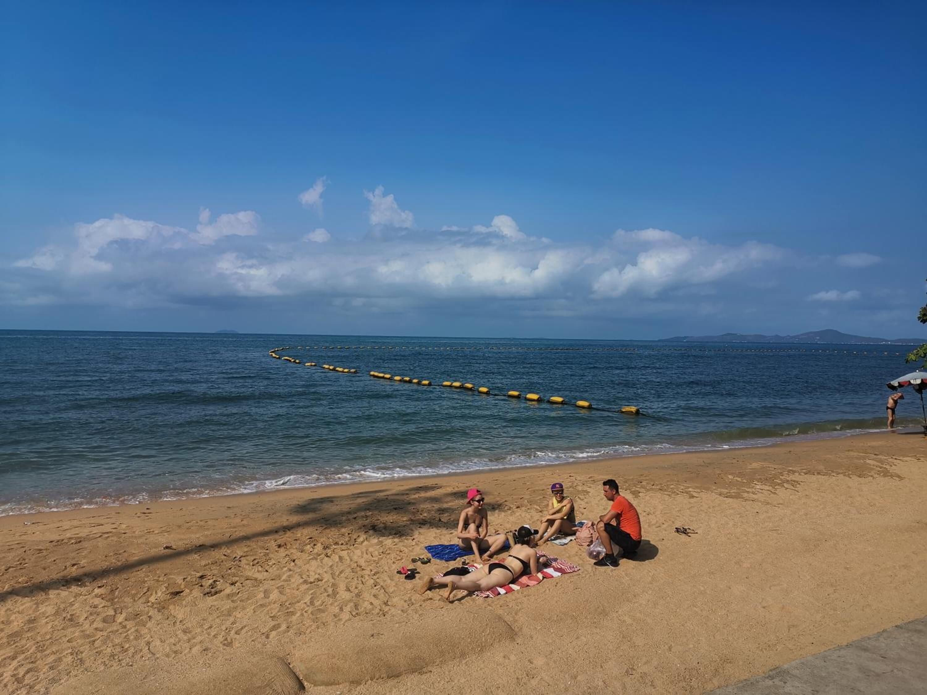 Une plage de sable fin, sous un ciel bleu clair et une mer calme.