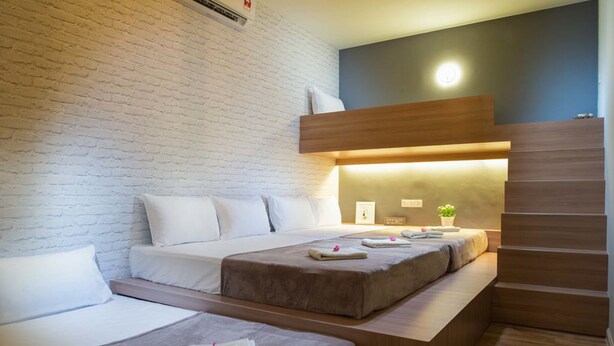 Habitació d'hotel amb paret de maó, fusta de capçal de llit i una cadira incorporada.
