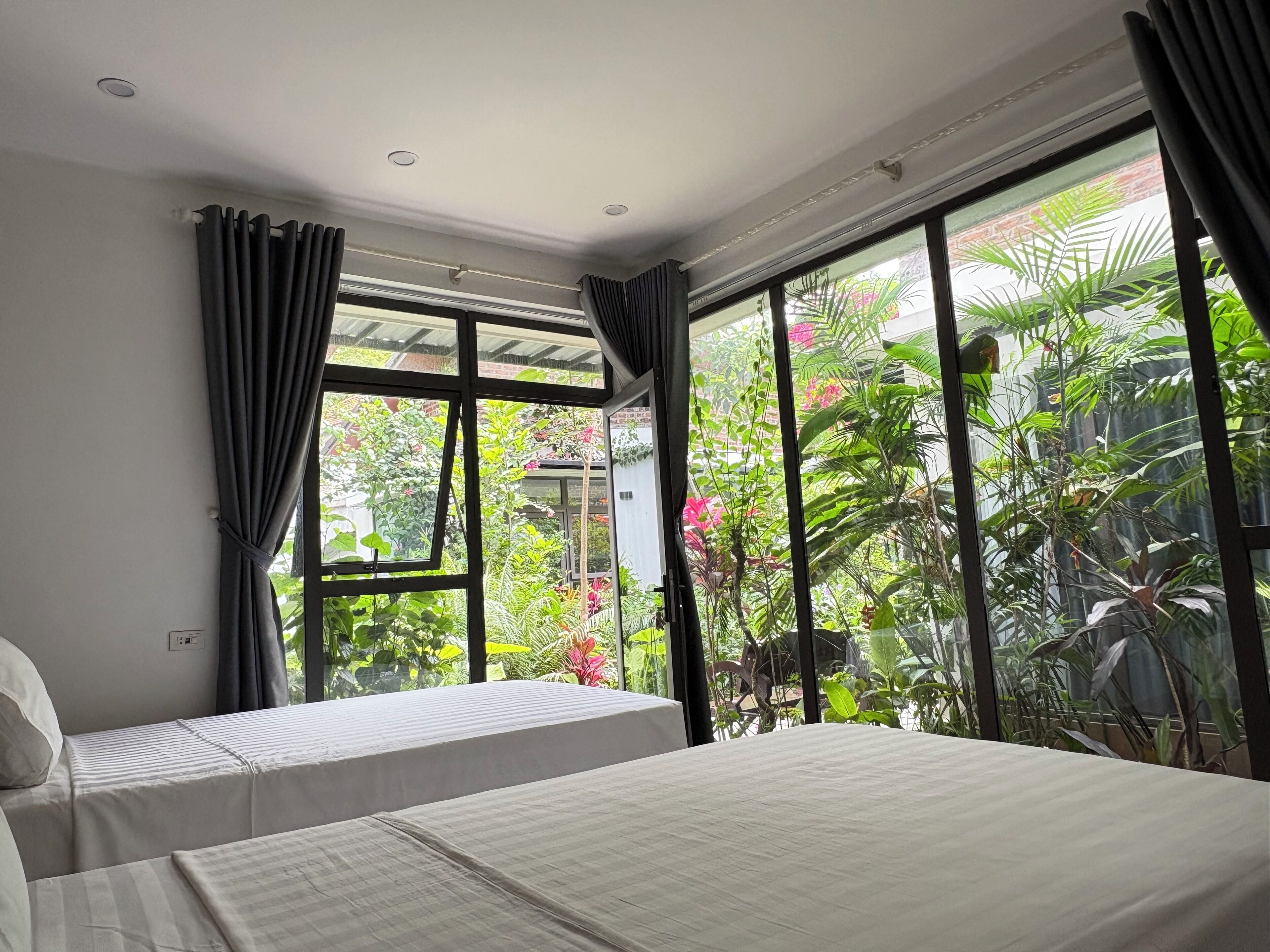 Camera da letto con due letti, ampie finestre e vista su un giardino.