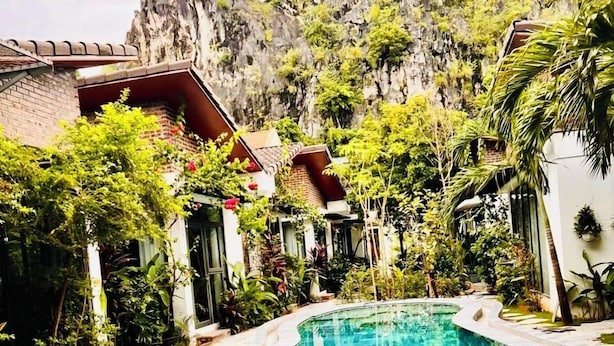 Une piscine dont le fond est décoré d’un motif en chevrons, entourée d’une végétation luxuriante et avec une chaîne de montagnes en toile de fond.