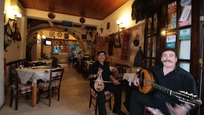 A rustic interior with wooden beams, a tiled floor, and tables with checkered tablecloths. - Chania Rooms (Chania)