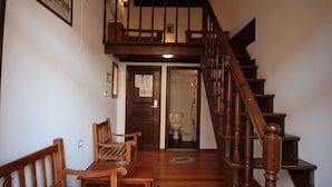A wooden staircase leading to an upper level, with a wooden bench and chairs on the lower level. - Chania Rooms (Chania)