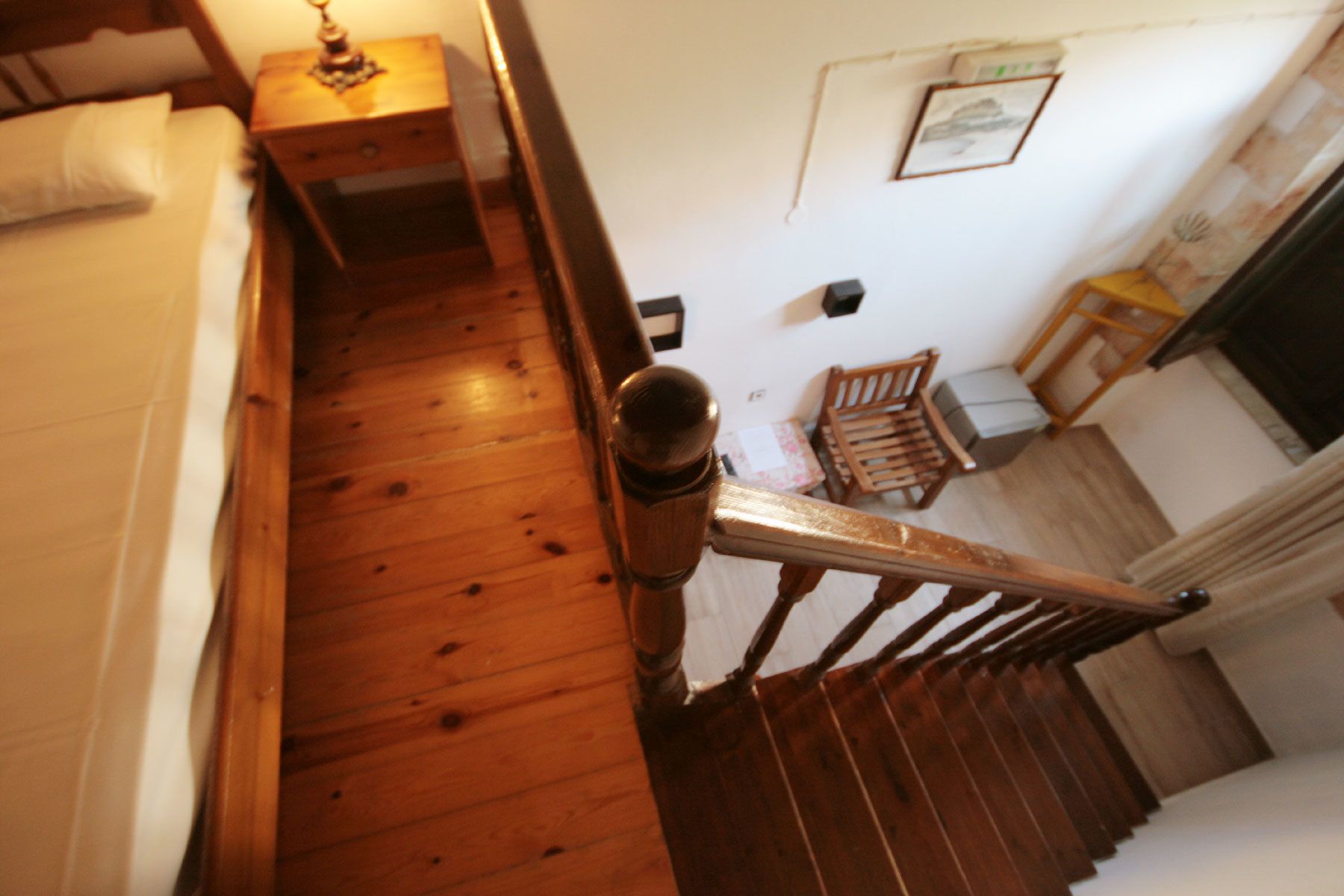 A wooden staircase with a handrail, a wooden bench, and a small table with a lamp.
