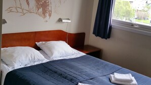 A hotel room with a bed, white pillows, a blue bedspread, and a wall mural of a bear. - Kirkenes Hotel (South Varanger)