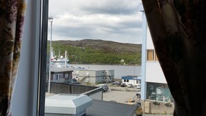 A window with floral curtains, a hanging lamp, and a small potted plant on a windowsill. - Kirkenes Hotel (South Varanger)