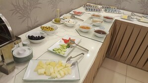 Een buffet met diverse soorten eten, waaronder fruit, groenten en toevoegingen.