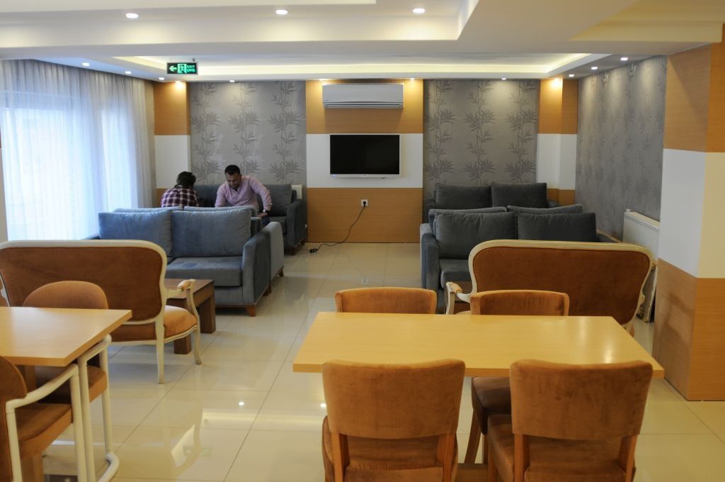 Vestíbulo de hotel con zonas de estar, televisor y una mesa.