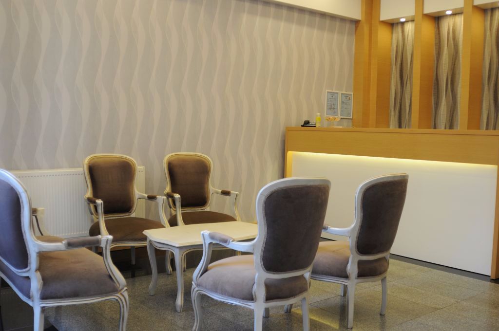 A reception area with a reception desk, two brown upholstered chairs, and a white table.