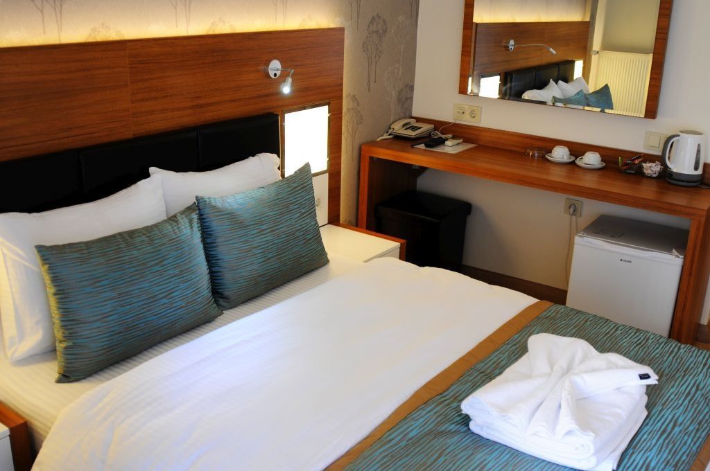 Une chambre d’hôtel équipée d’un lit, d’un bureau, d’un miroir, d’un téléphone et d’une machine à café.