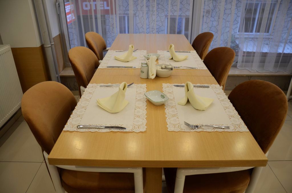Un tavolo da pranzo apparecchiato con tovaglioli bianchi, posate e un centrotavola decorativo.