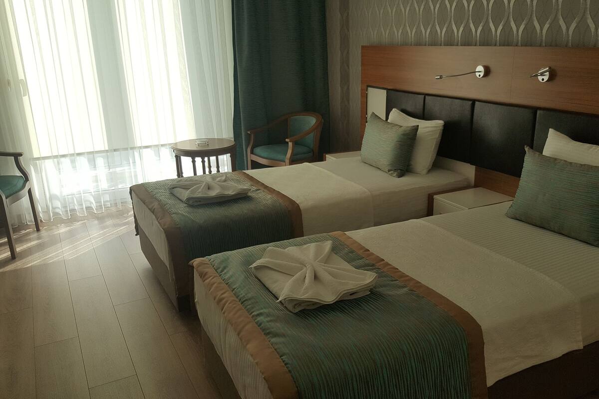 Une chambre d’hôtel avec deux lits, une tête de lit en bois, une petite table et une chaise.