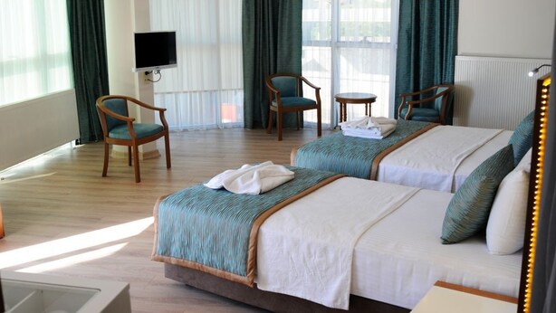 Een hotelkamer met twee bedden, een televisie en een zithoek met stoelen en een tafel.