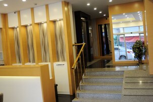 A szálloda recepciónál található egy lépcsőház, egy recepciós pult, és kilátás nyílik a parkolóról.