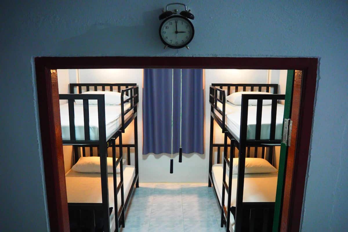 A room with two bunk beds, a clock on the wall, and a curtain.